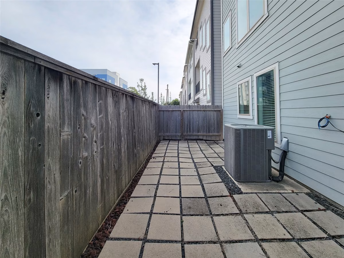 Charming side patio with clean, modern pavers and a private fenced enclosure, perfect for outdoor relaxation.