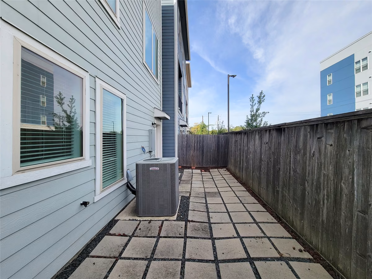 Charming side yard with modern siding, featuring a paved walkway and privacy fence, ideal for outdoor relaxation.