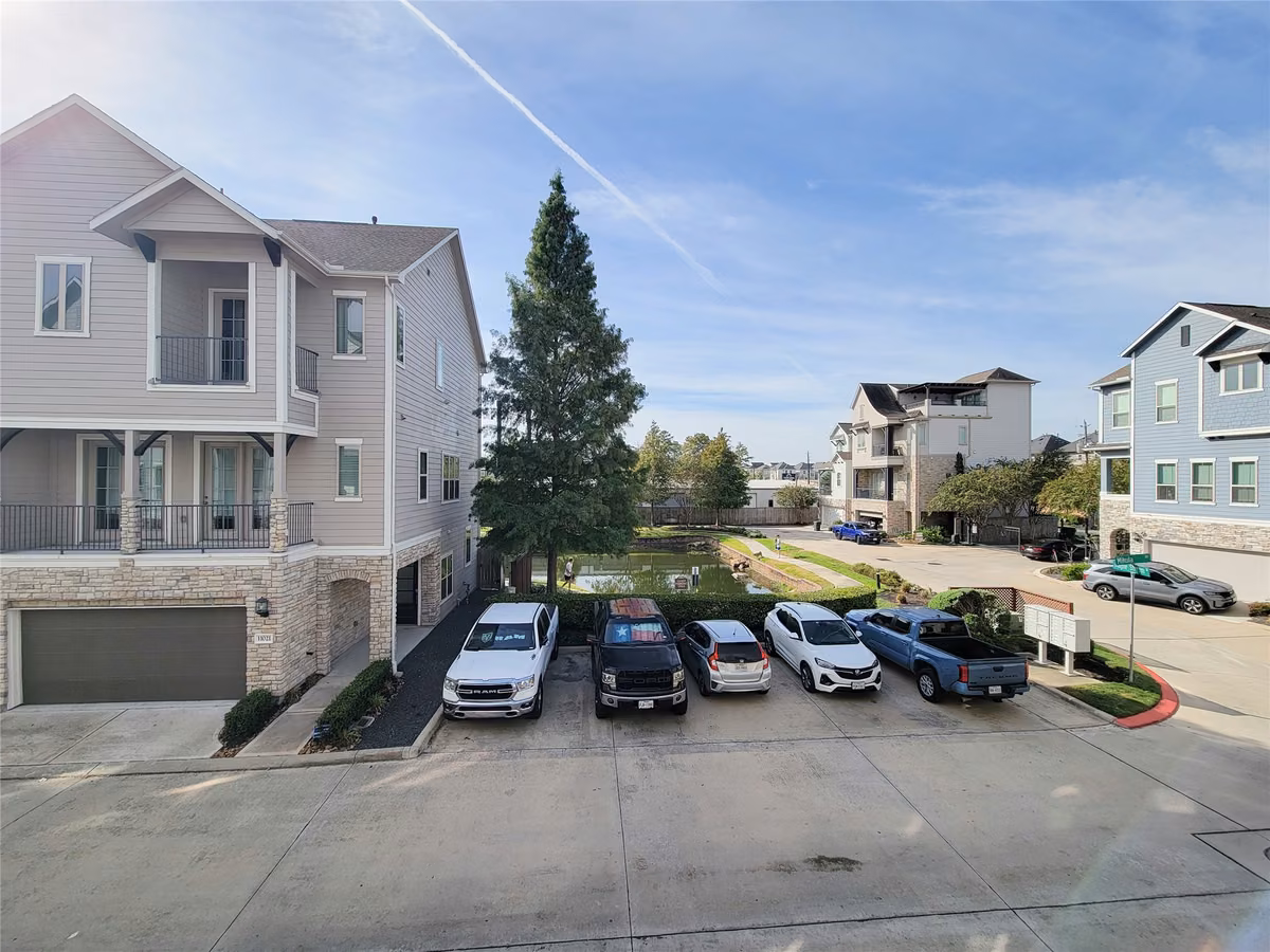 Modern three story townhomes with balconies and garage access, set in a well maintained neighborhood featuring ample parking and landscaped communal areas.