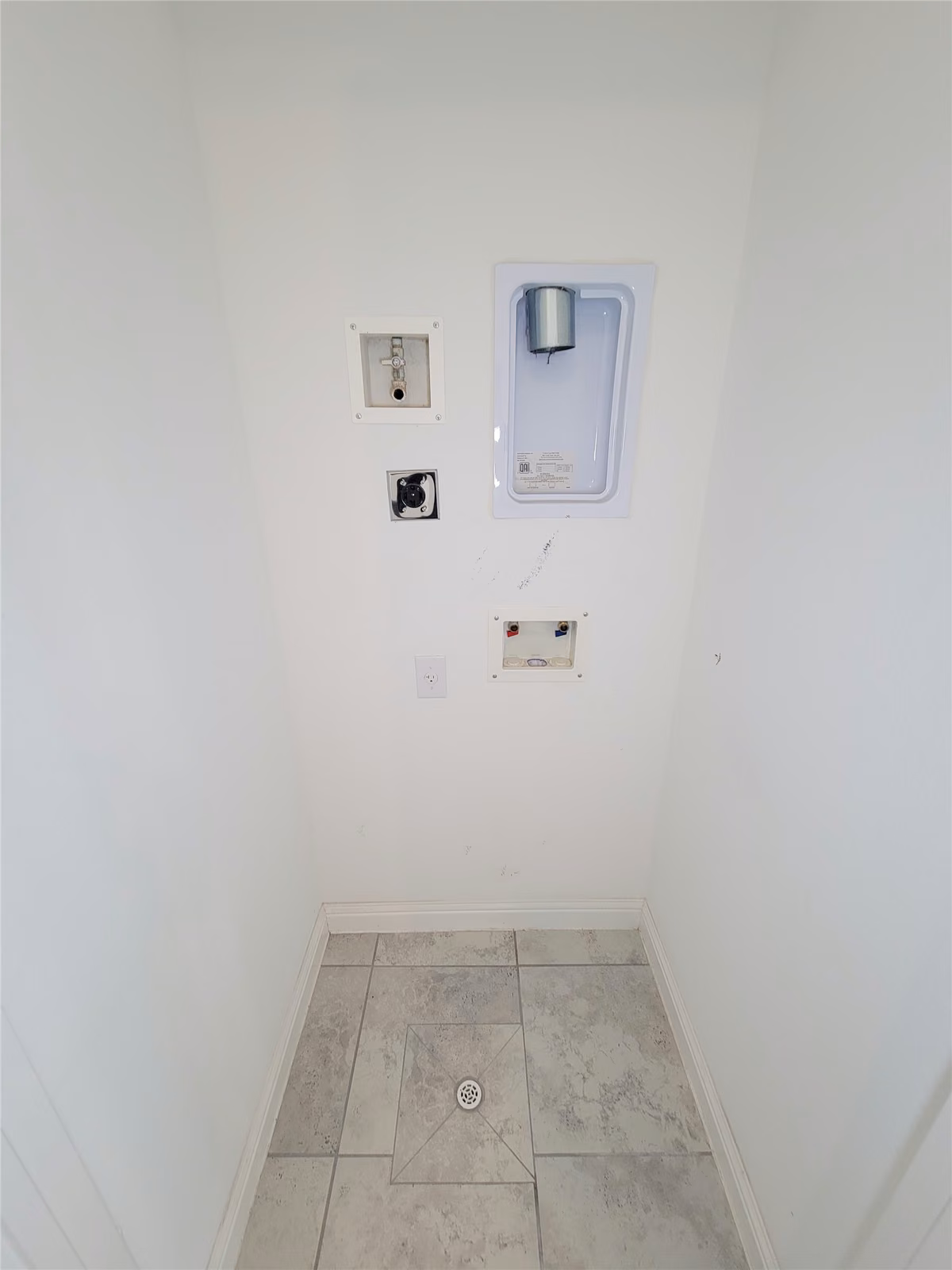 Laundry area with hookups for washer and dryer, featuring clean tile flooring and utility connections.