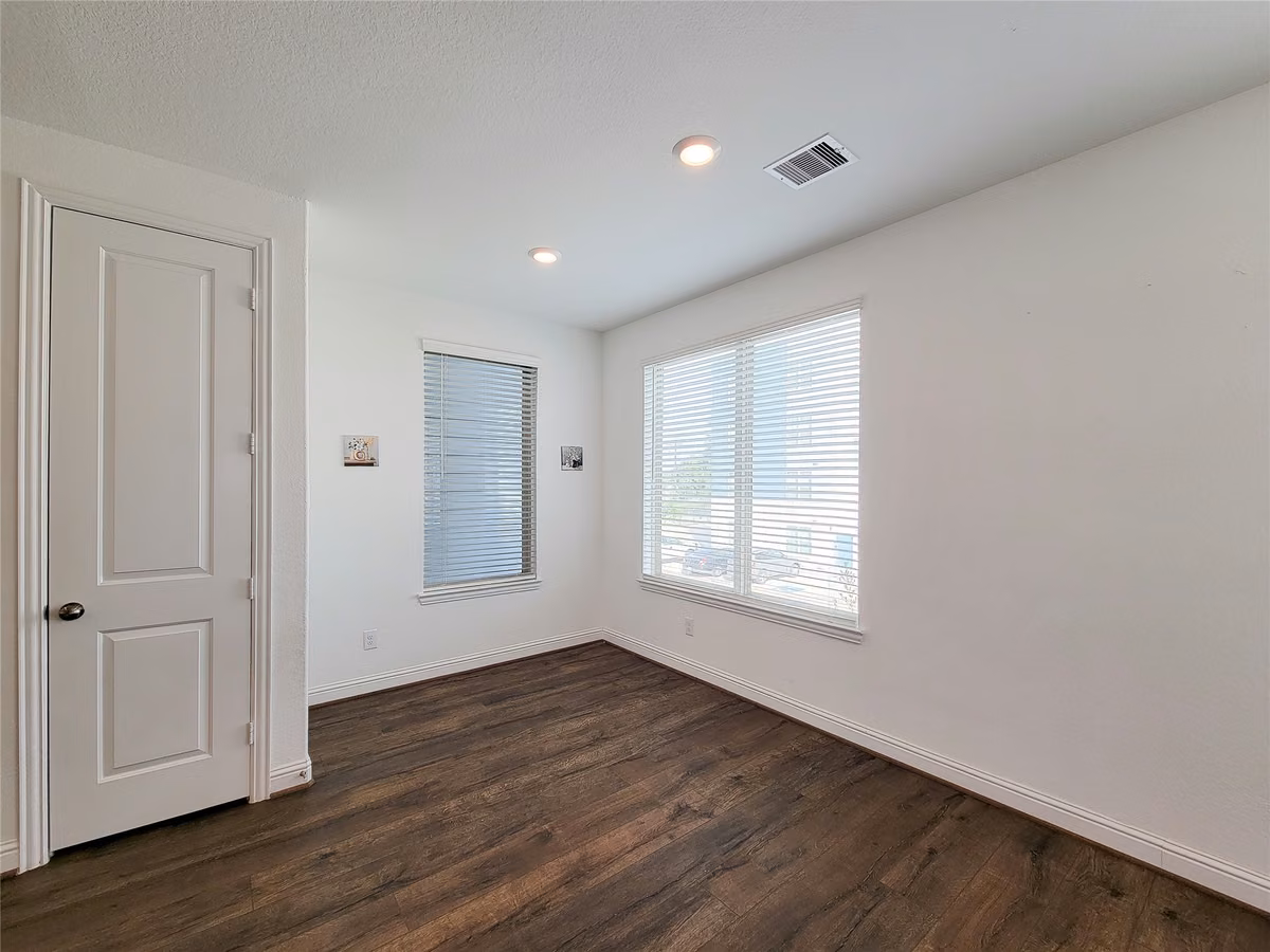 Bright and spacious room with sleek hardwood flooring, large windows for natural light, and a modern, clean design.