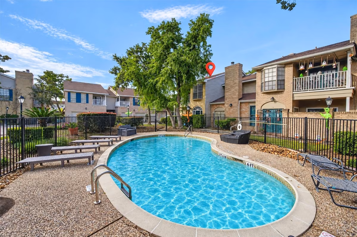 Community pool surrounded by mature trees and landscaped gathering areas.