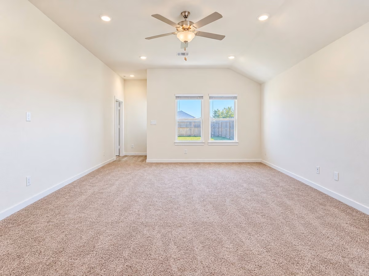 Spacious living area with plush carpeting, recessed lighting, and a ceiling fan, offering a cozy and inviting atmosphere.
