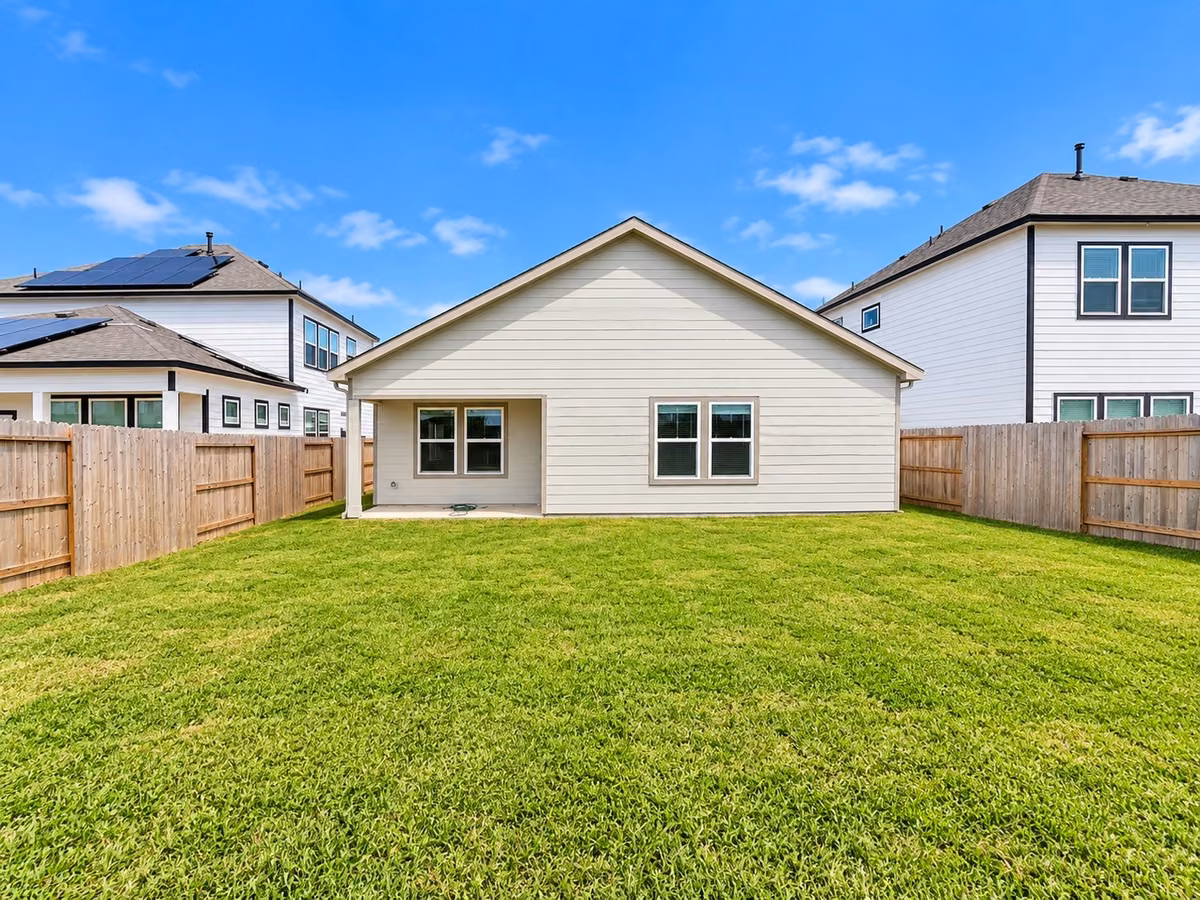 Spacious backyard with well-maintained lawn and a cozy covered patio, perfect for outdoor activities and relaxation.