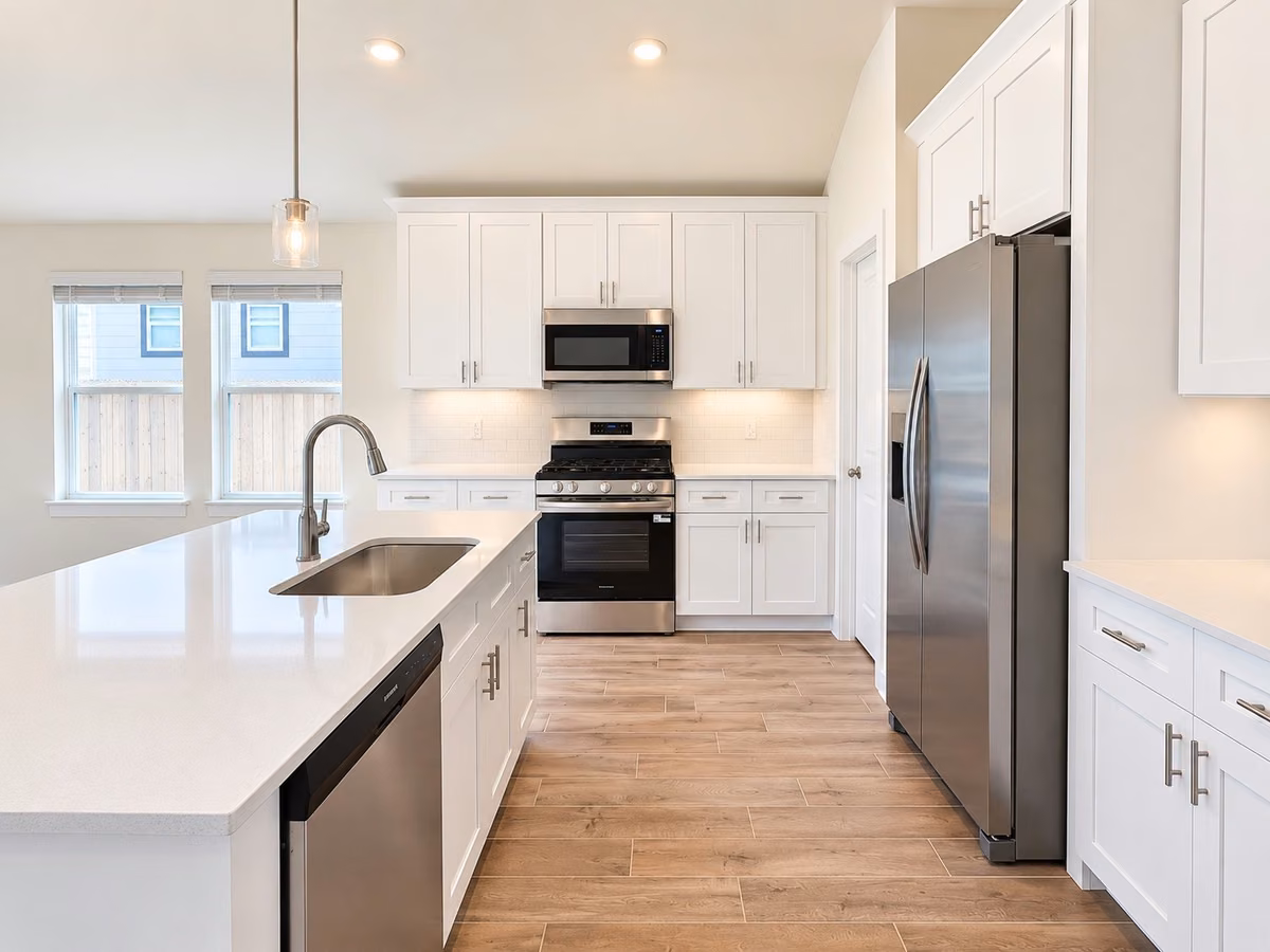 Modern kitchen with sleek stainless steel appliances, a spacious island with a sink, and bright white cabinetry, creating a clean and inviting space.